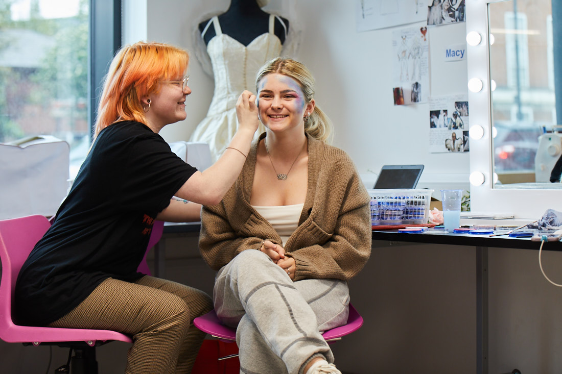 A female student having her face painted by another student