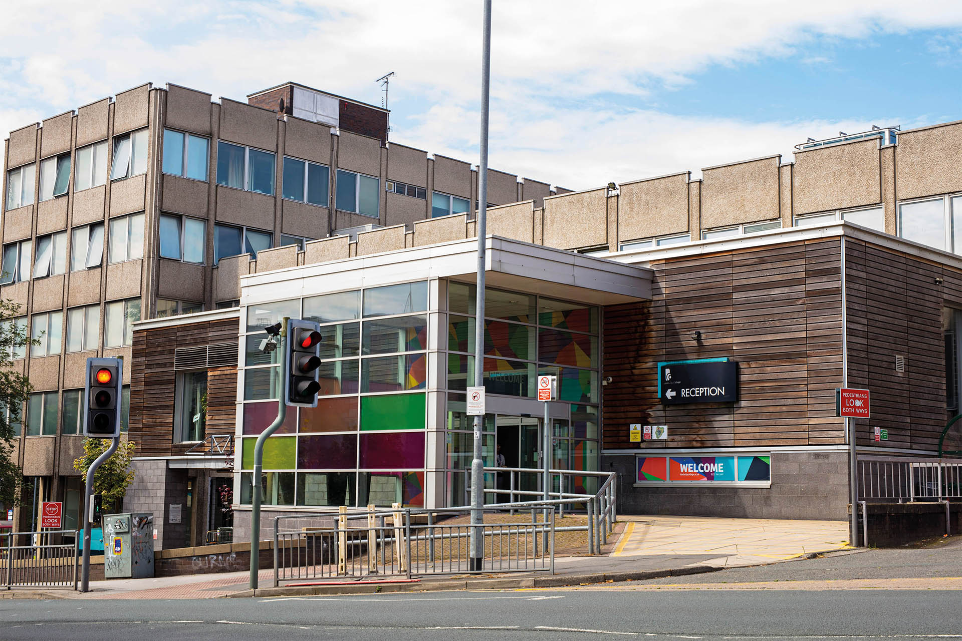 A view of the Park Lane campus entrance and building in summer with blue skies and white clouds