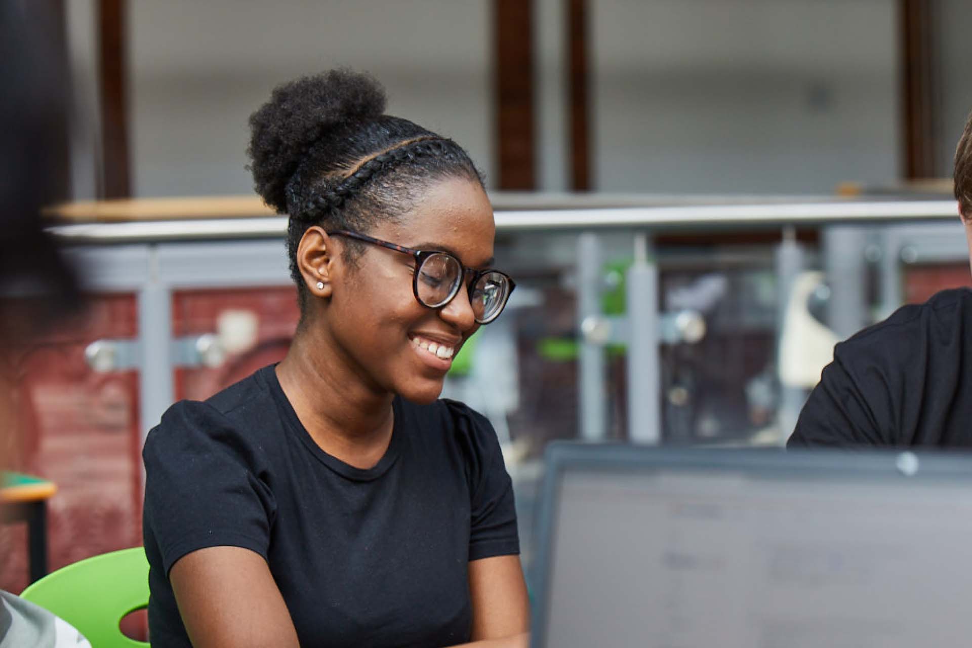 Student wearing glasses looking down and smiling