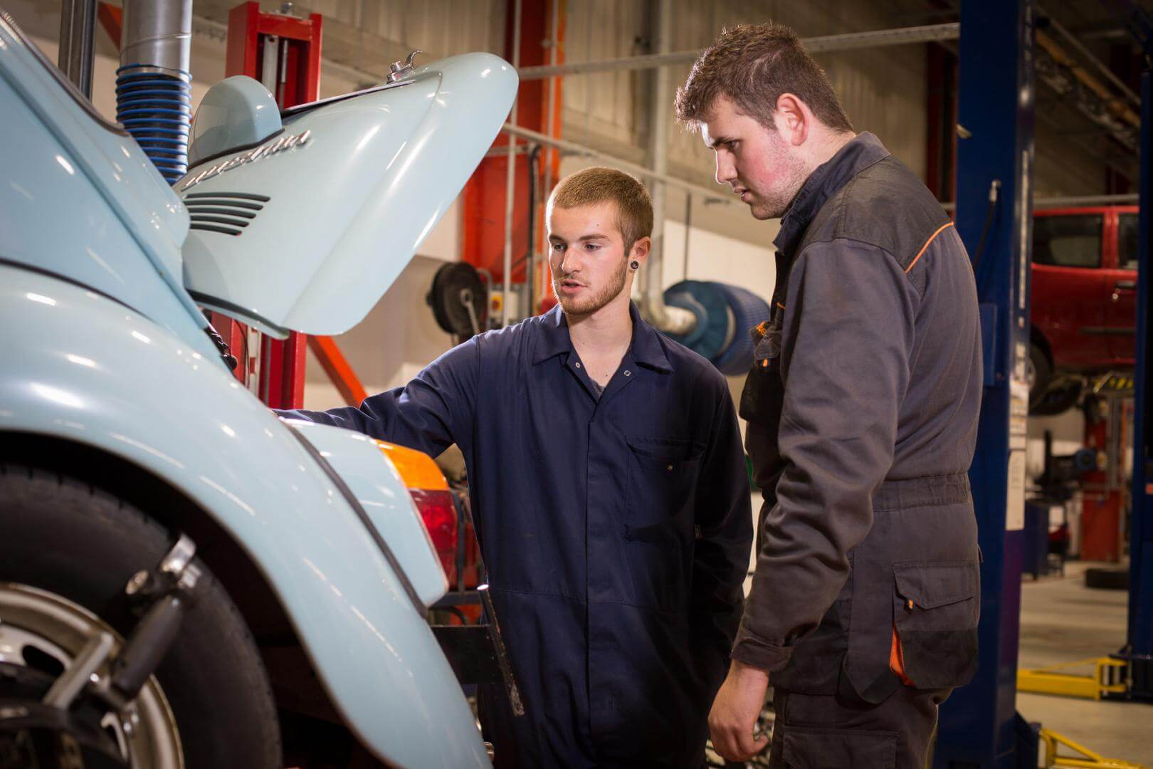 Automotive tutor showing a student the engine of a car