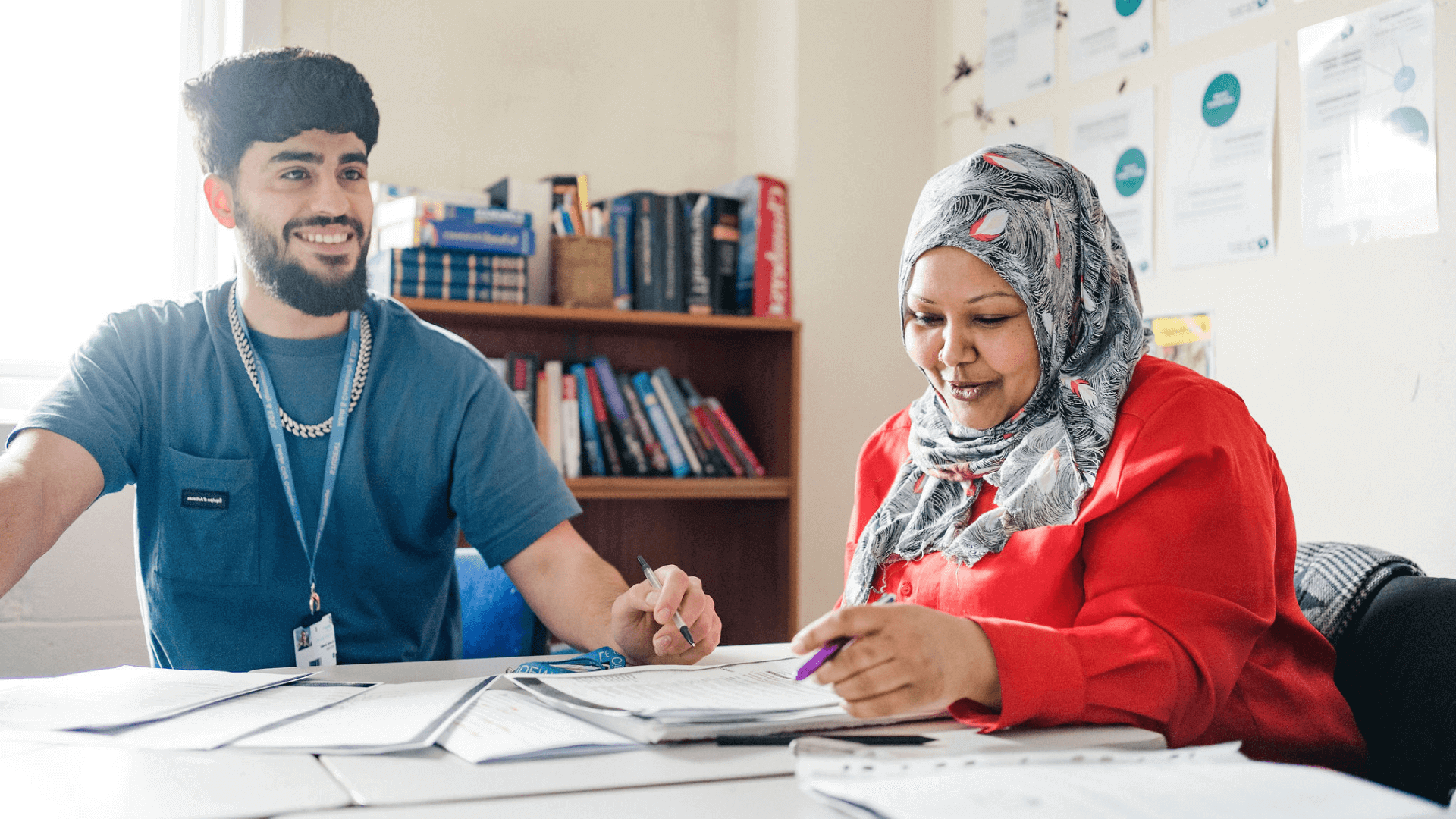 Two adult students sat in a classroom looking at a text book