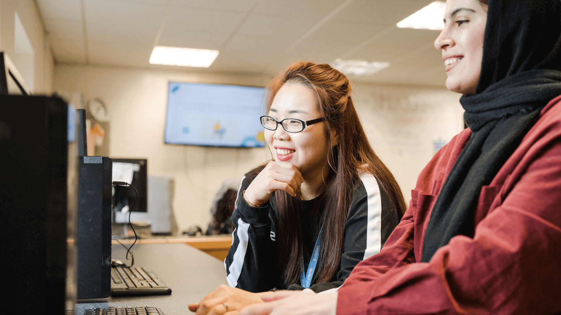 Adult learners working on computers smiling