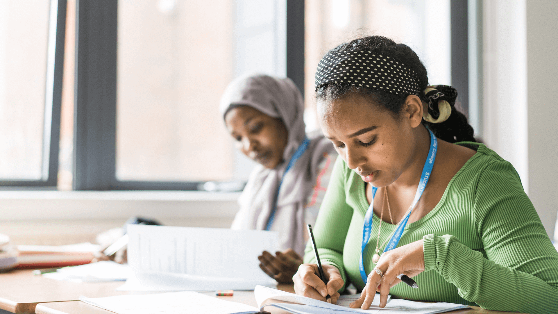 Two students deep in study writing notes