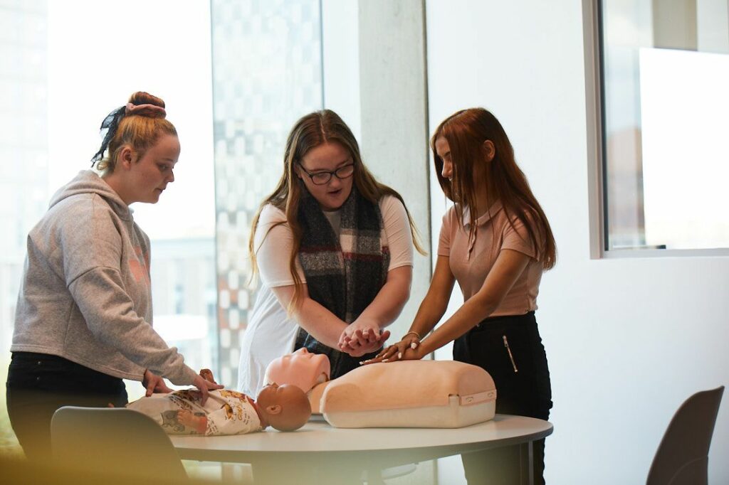 Group of students learning how to perform CPR on a baby/toddler