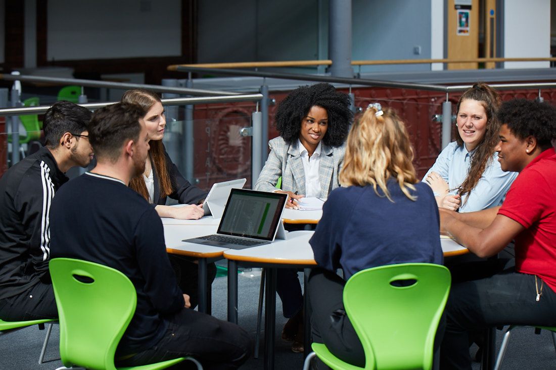 Business students sat round a circular table having a discussion