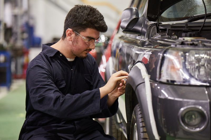 Motor Vehicle student masking off the wheel arch of a Jeep
