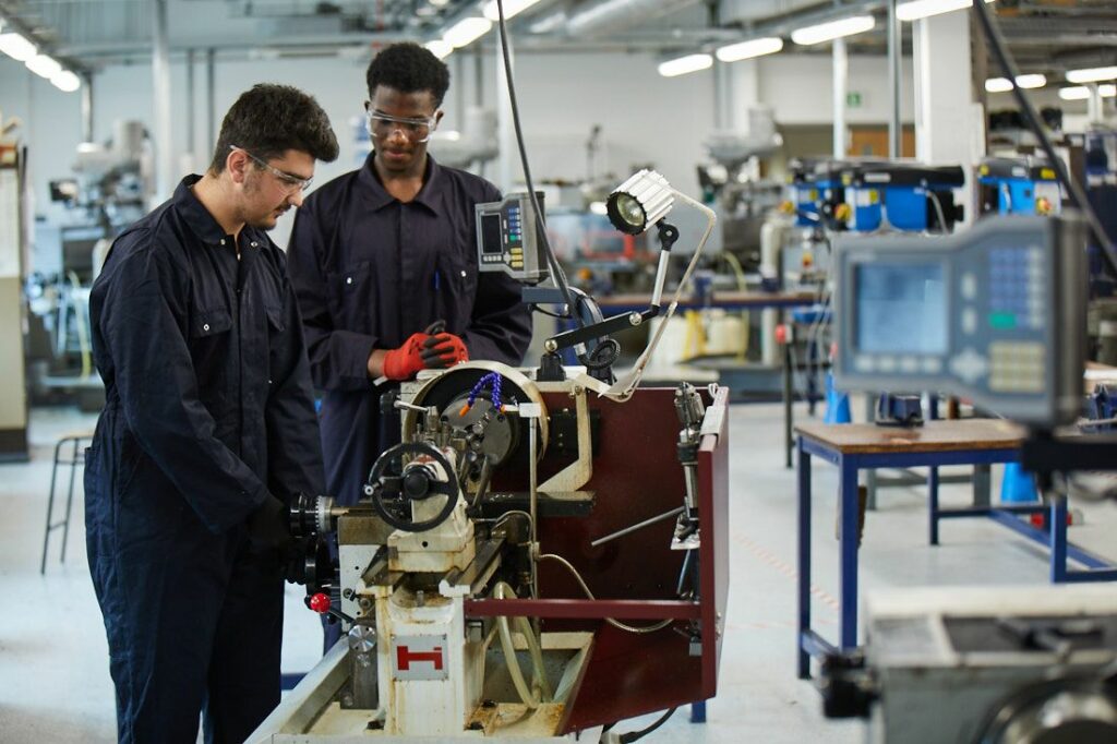 LCC Engineering students wearing overalls working on machinery
