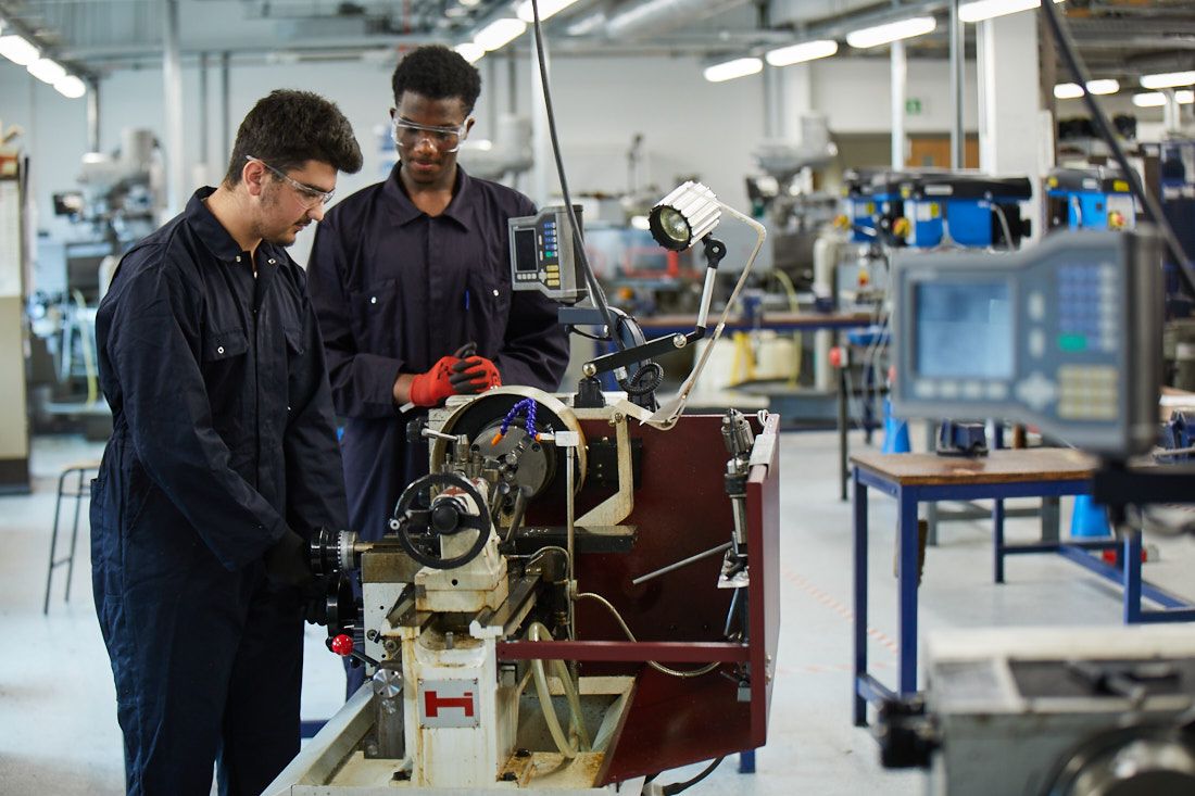 LCC Engineering students wearing overalls working on machinery