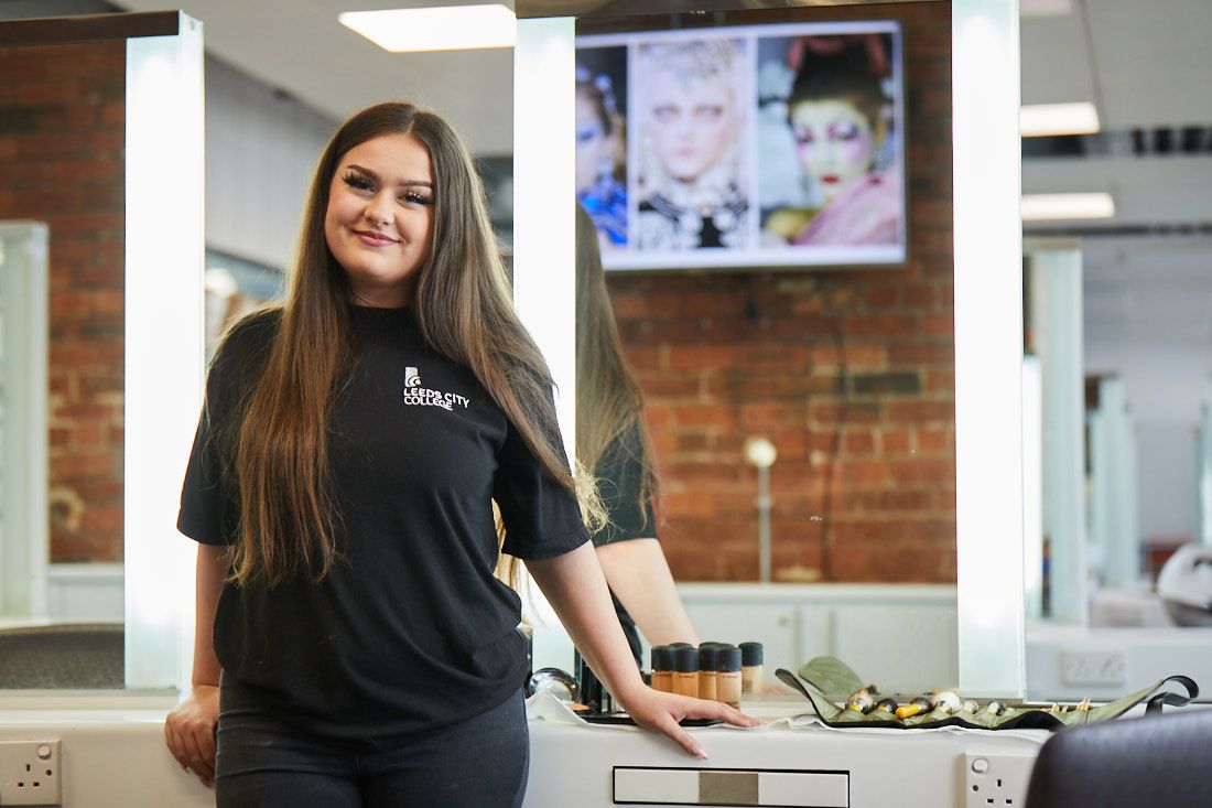 LCC Hair and Beauty student posing for a photo next to make up and brushes
