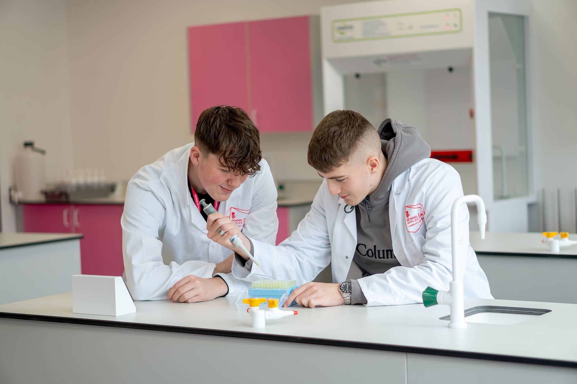 Two LCC Applied Science students working on an experiment putting chemicals in to test tubes