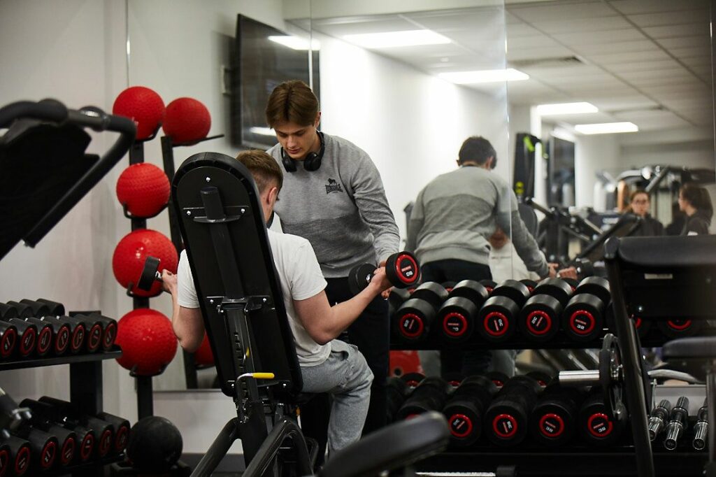 Sports coaching student assisting another student doing an exercise