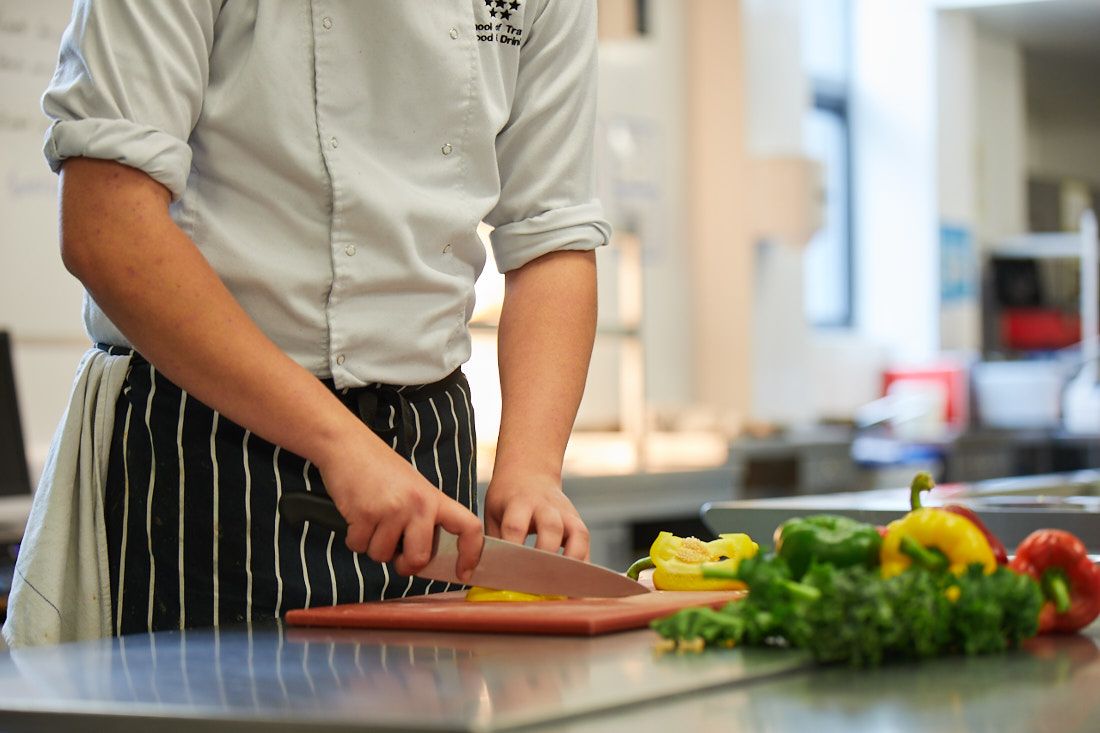 Leeds City College Travel Food and drink student cutting vegetables in the student kitchens