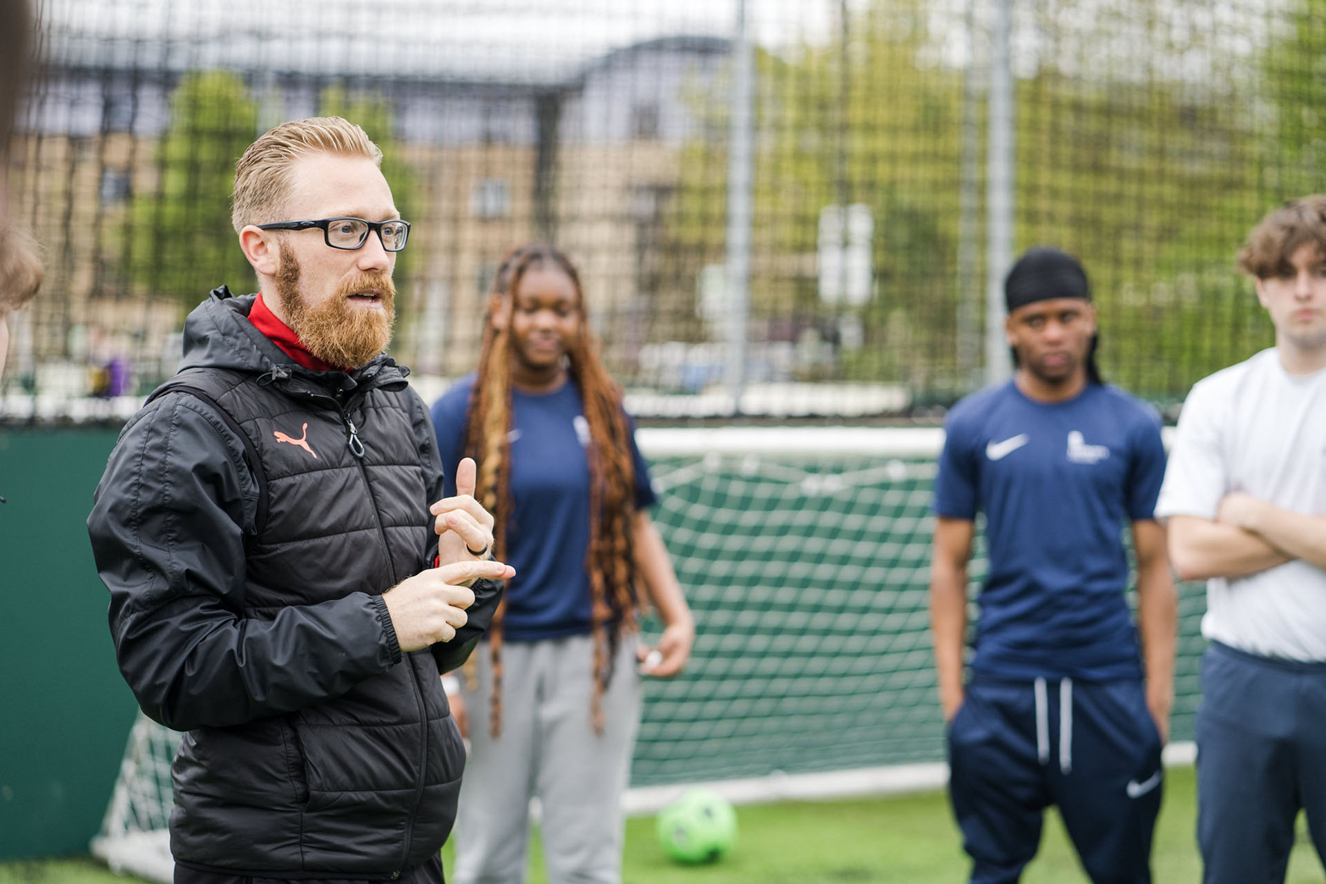 Sport tutor teaching a class out on the playing field