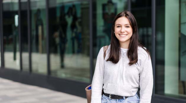 Student stood outside Leeds City College building smiling at the camera