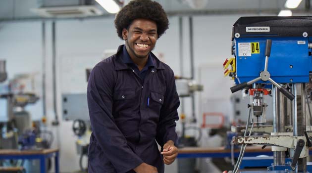 Engineering apprentice at Leeds City College smiling wearing engineering overalls