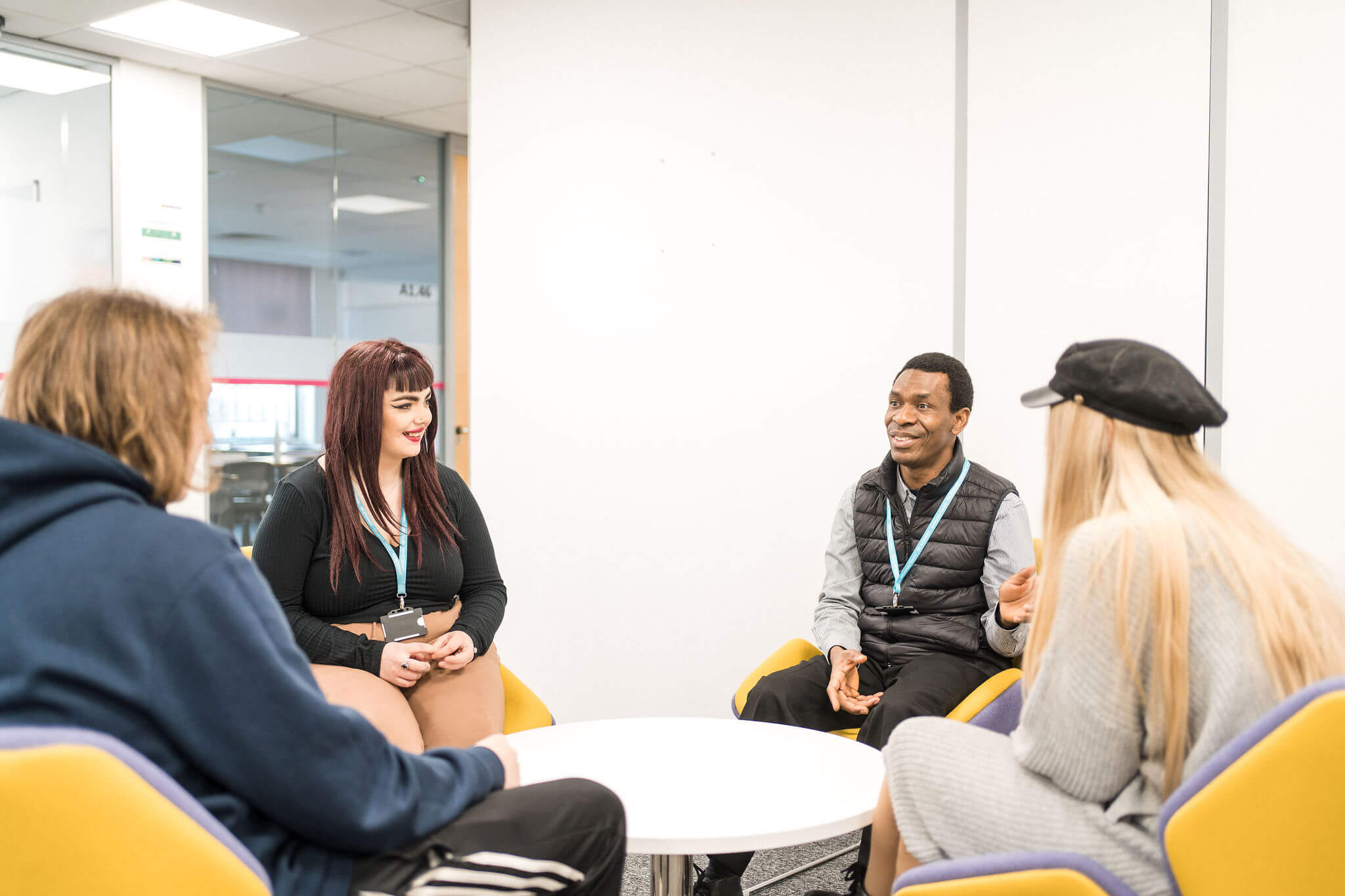 Four higher education students sitting facing each other having discussion