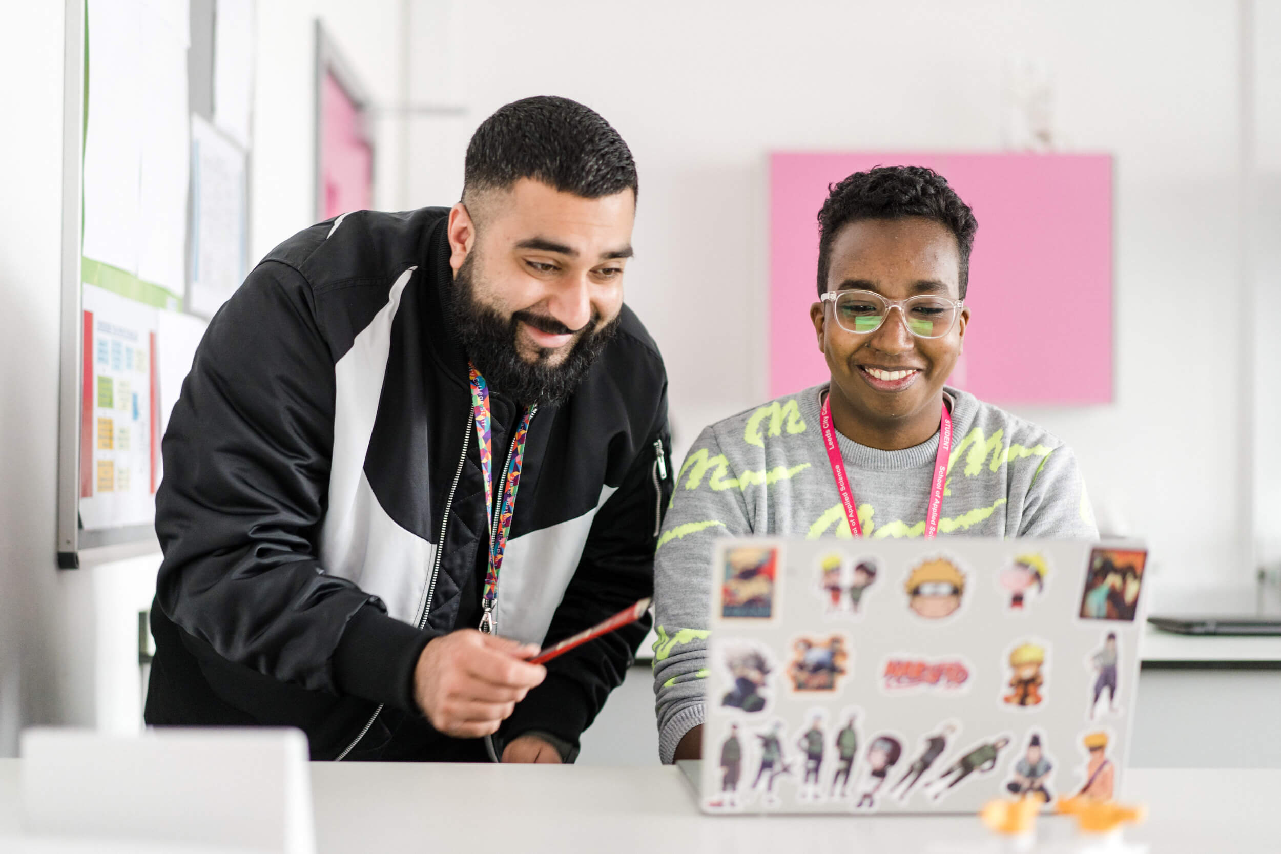 Two students looking at the laptop smiling in the classroom