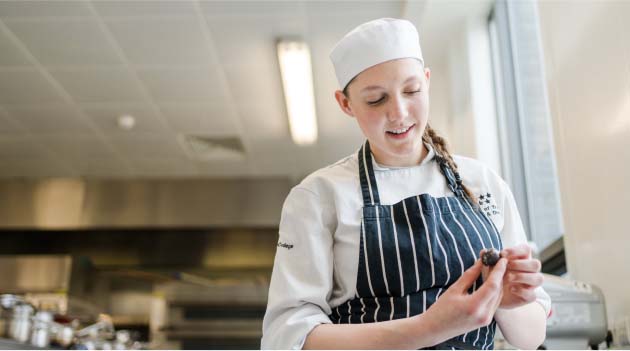 Catering and Hospitality apprentice wearing chef overalls in the Printworks kitchens
