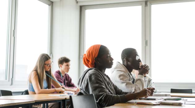 Students sat at desks in a classroom looking towards the front of the classroom