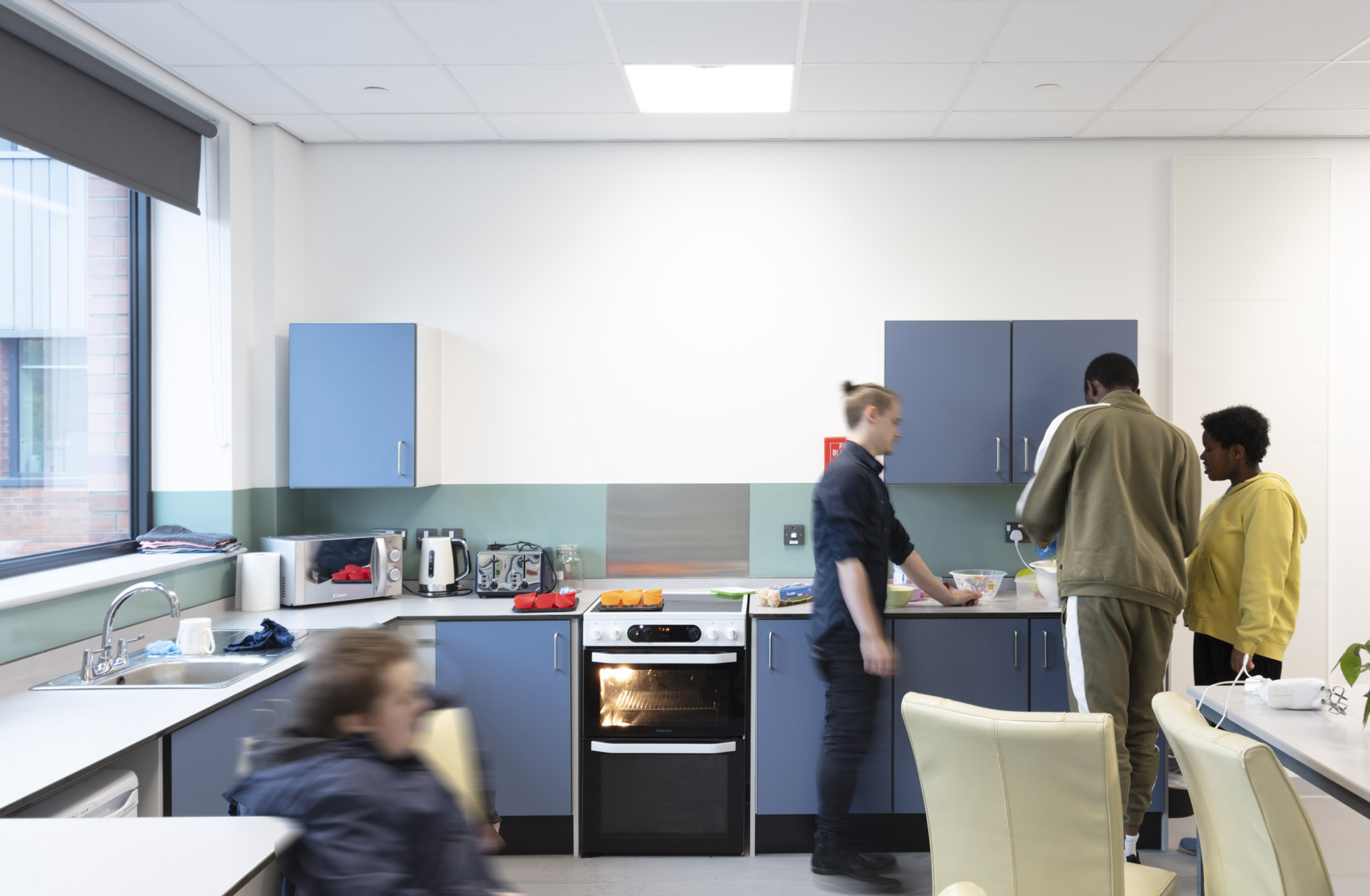 Tutor helping students preparing food in a kitchen full of appliances