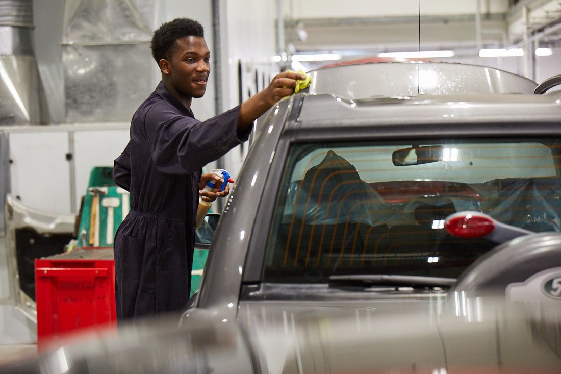 Student mechanic spraying a car with a wax wash