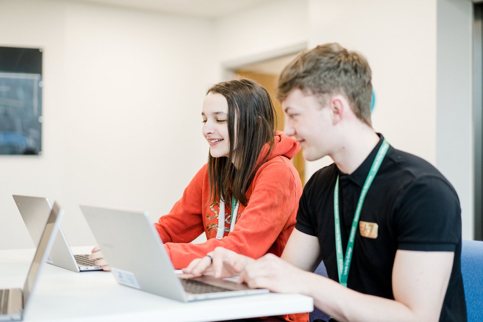 Two public services students in class working on their laptops