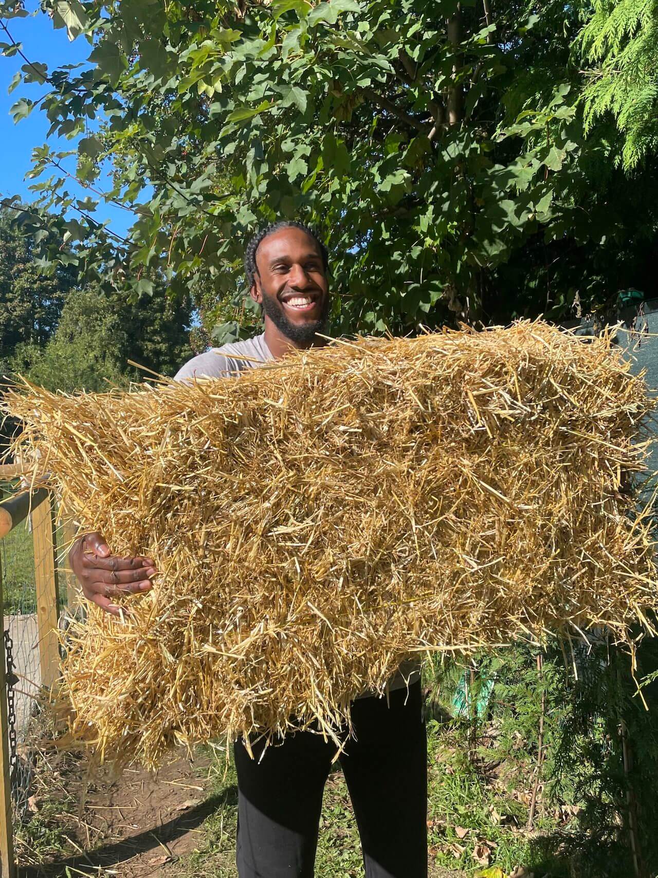 Karl Jones holding up a hay bale smiling