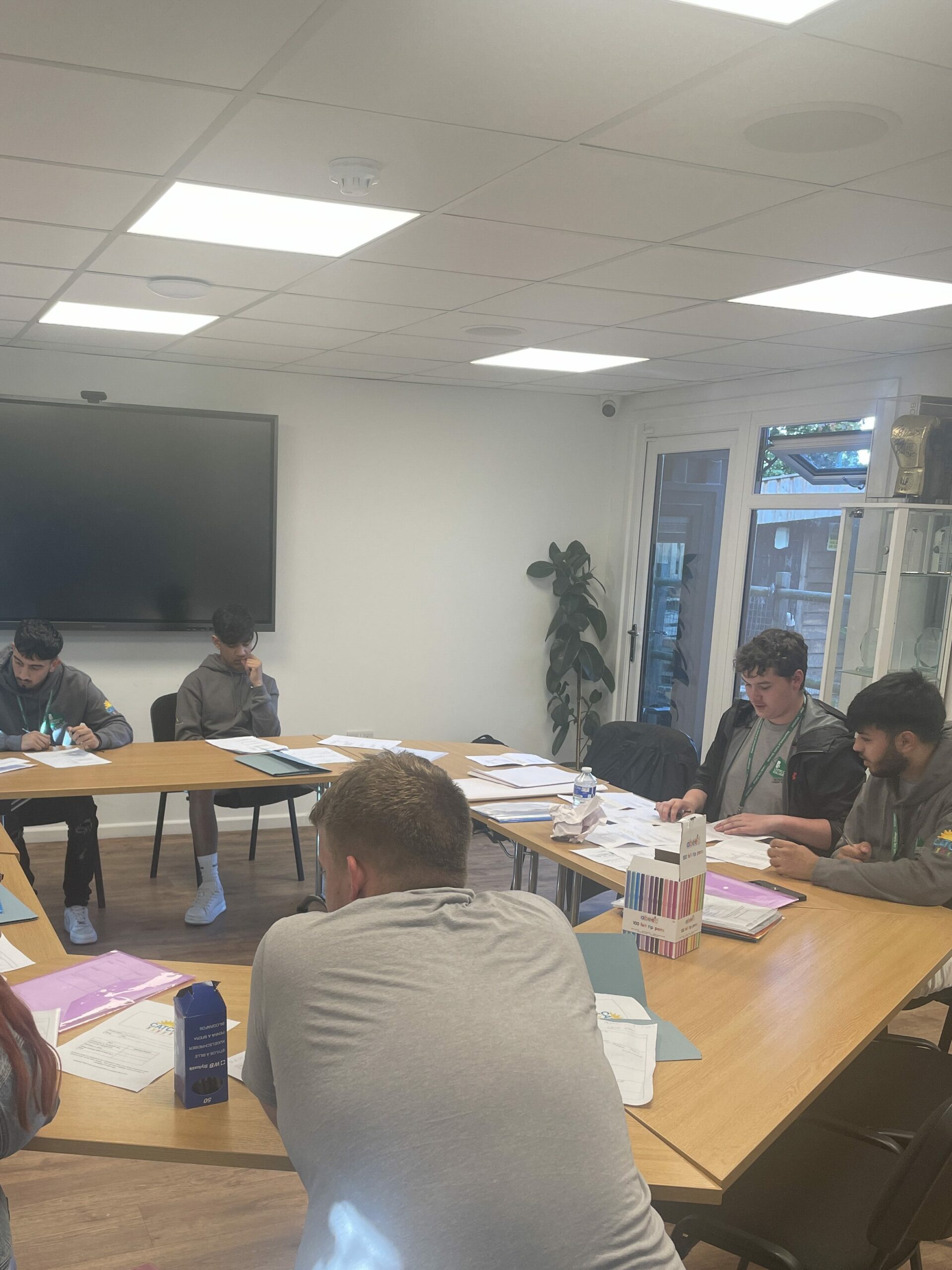 Students sat at desks in classroom looking down at papers and working in pairs