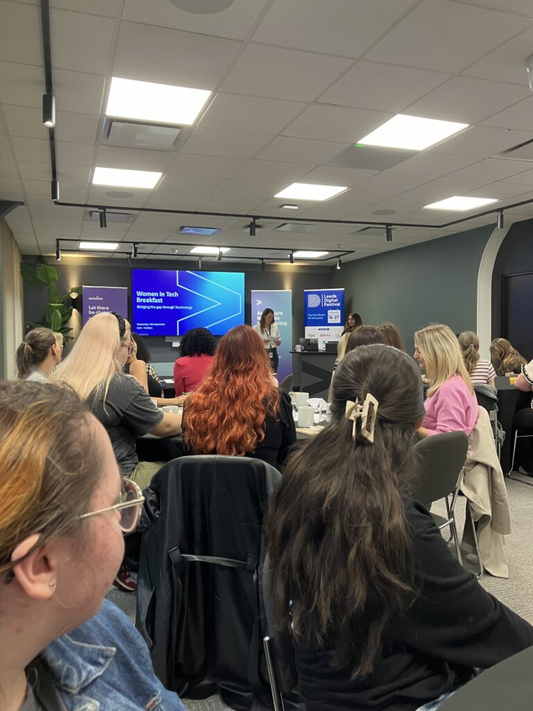 A speaker presents to crowded room of women as part of the Women in Tech Breakfast