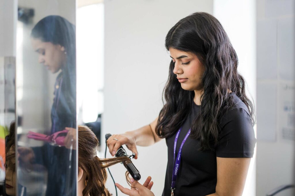 Hairdressing student at Leeds City College Printworks campus learning to curl hair with a curling tong