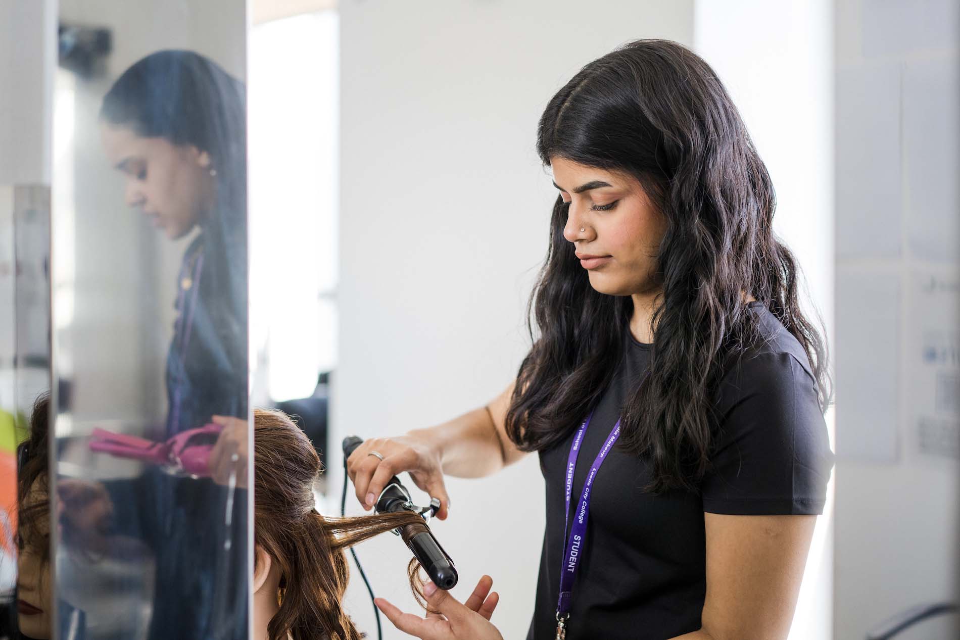 Hairdressing student at Leeds City College Printworks campus learning to curl hair with a curling tong