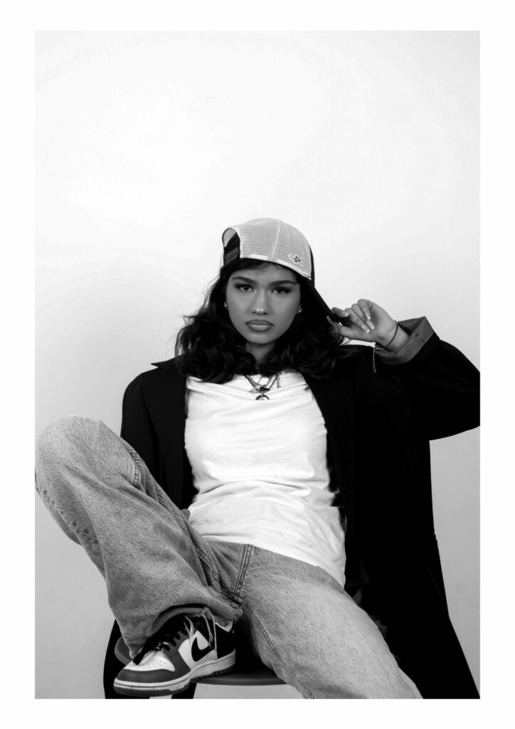 Creative arts students photography in black and white of a women wearing trendy clothing sitting down posing