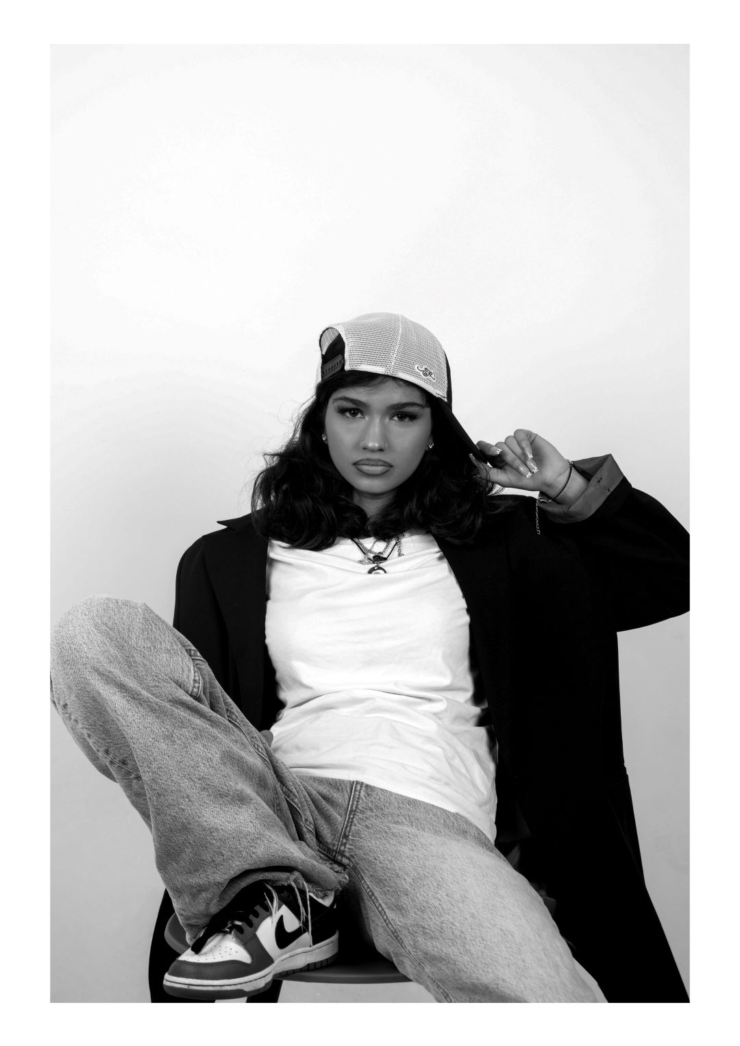 Creative arts students photography in black and white of a women wearing trendy clothing sitting down posing