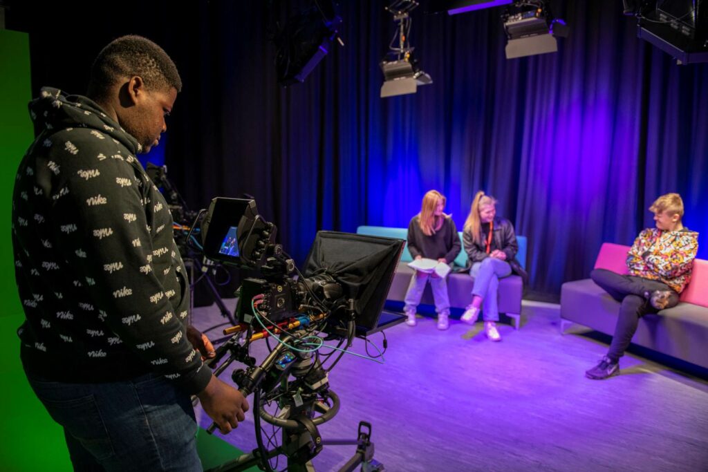 Creative Arts TV and Media students hosting a televised interview with each other with another student being the camera operator