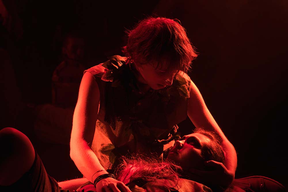 One acting student is holding another student in an embrace in onstage performance