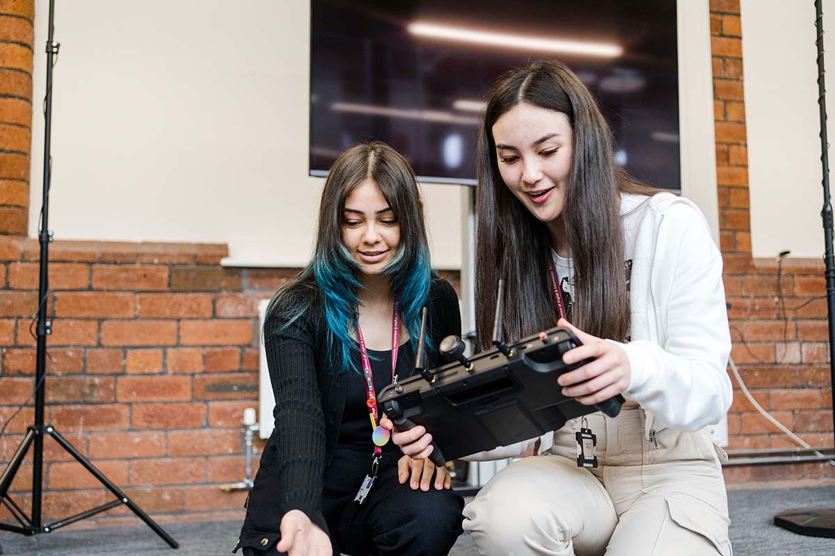 Two students looking at a controller device in studio classroom