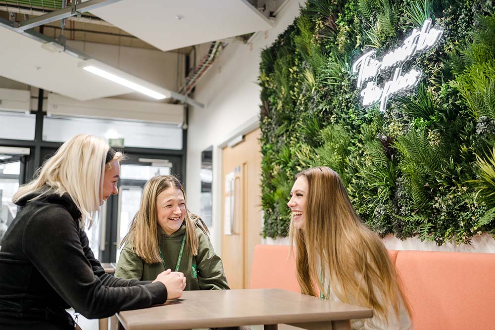 Three female students sat down chatting and laughing