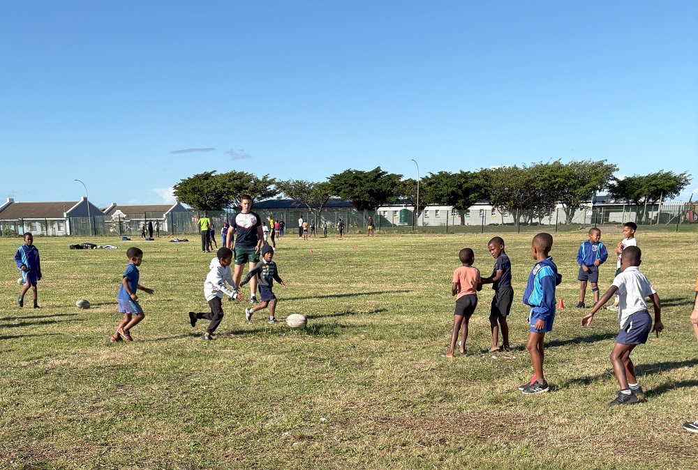 A Sports student from Leeds City College coaching South African school children during a football match