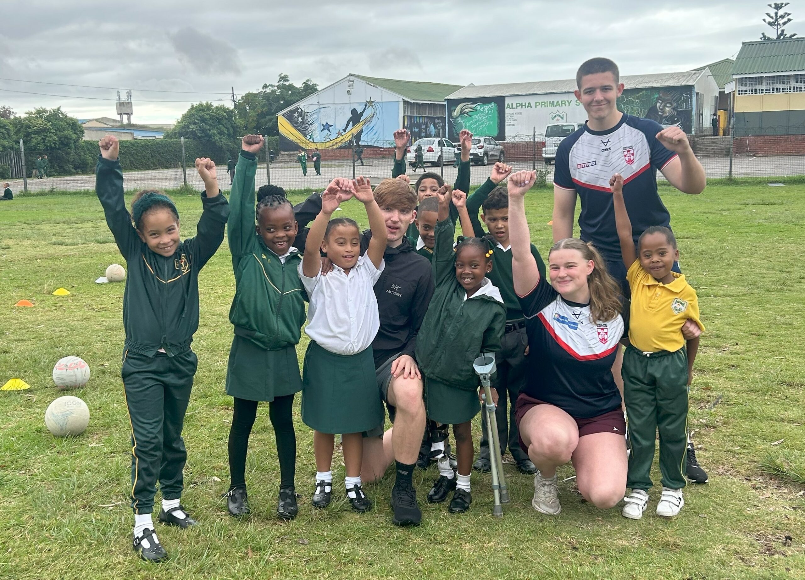 Sports students from Leeds City College cheering beside local school children during their trip to South Africa